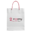 A white paper shopping bag with pink handles and the Zoopsy logo printed on the front, set against a neutral gray studio background.